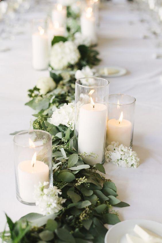 Camino de mesa con hojas verdes y flores blancas 